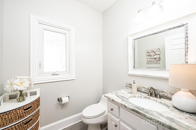 bathroom featuring baseboards, vanity, and toilet