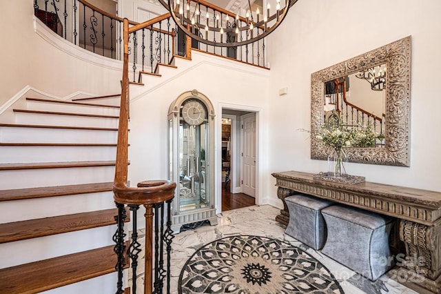 entryway with stairs, a high ceiling, a chandelier, and baseboards