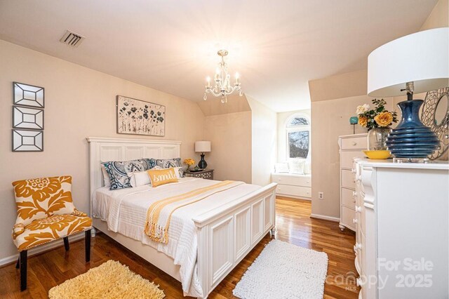 bedroom with lofted ceiling, a notable chandelier, wood finished floors, visible vents, and baseboards