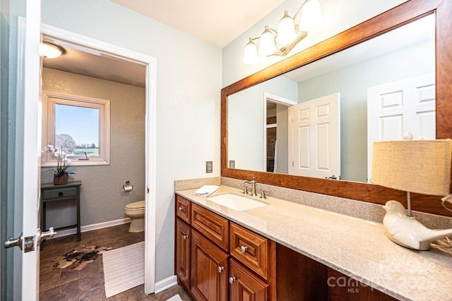 bathroom with baseboards, vanity, and toilet