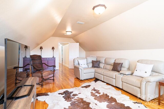 living area featuring visible vents, vaulted ceiling, and light wood-style flooring