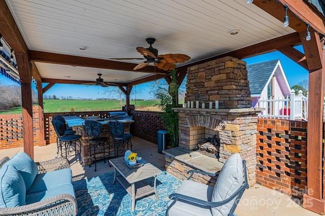 view of patio featuring ceiling fan, an outdoor living space with a fireplace, and outdoor dry bar