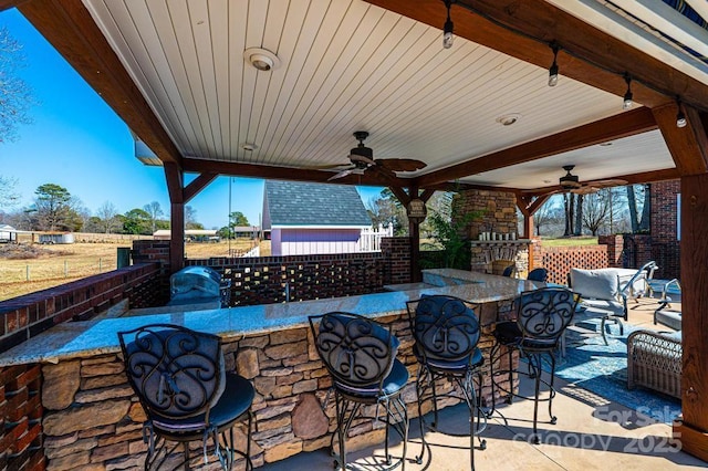 view of patio / terrace with a ceiling fan, fence, and outdoor dry bar