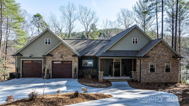 craftsman-style house with driveway, central AC unit, stone siding, an attached garage, and board and batten siding