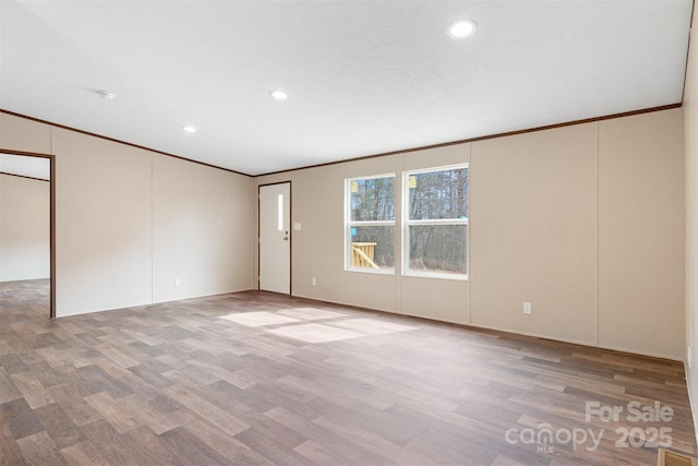 empty room with light wood finished floors, recessed lighting, and crown molding