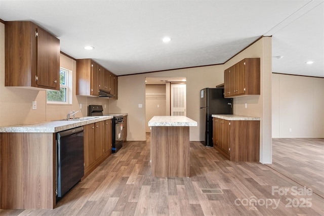 kitchen with light wood-style flooring, a kitchen island, light countertops, brown cabinets, and black appliances