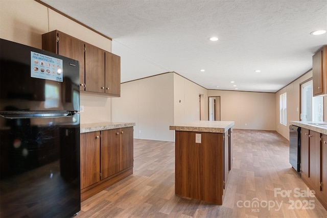 kitchen featuring brown cabinets, freestanding refrigerator, light countertops, and light wood finished floors