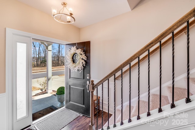 foyer featuring stairway, dark wood-style flooring, and a notable chandelier