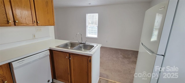 kitchen with light colored carpet, white appliances, a sink, light countertops, and brown cabinets