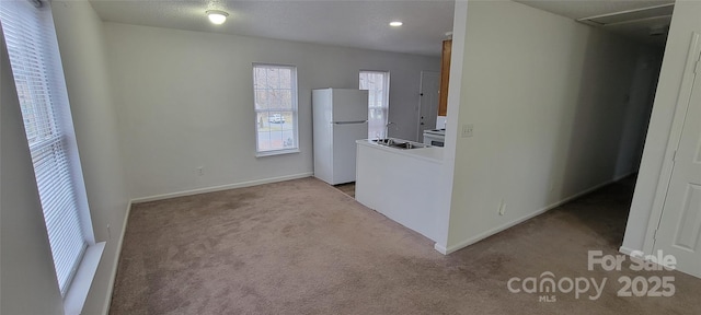 unfurnished room with light colored carpet, a sink, and baseboards