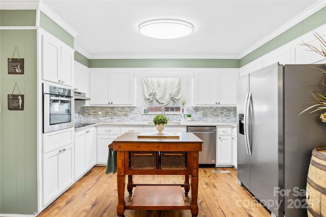 kitchen with appliances with stainless steel finishes, light countertops, crown molding, and under cabinet range hood