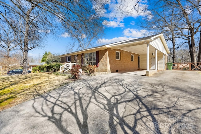 view of front of property with crawl space, driveway, an attached carport, and brick siding