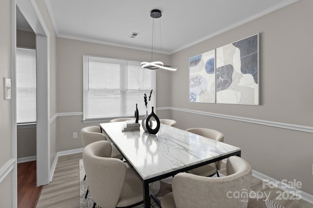 dining area featuring ornamental molding, light wood-type flooring, visible vents, and baseboards