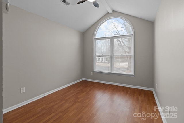 empty room featuring vaulted ceiling with beams, wood finished floors, a ceiling fan, visible vents, and baseboards