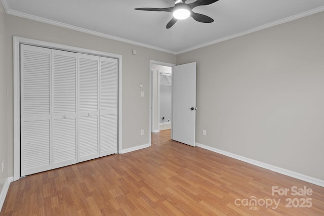 unfurnished bedroom with light wood finished floors, baseboards, ceiling fan, crown molding, and a closet