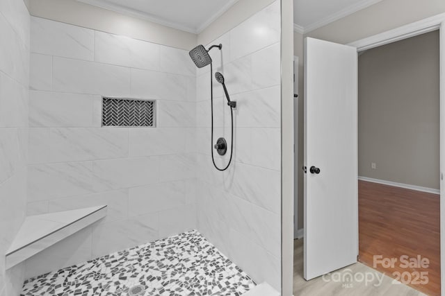 bathroom featuring ornamental molding, a tile shower, baseboards, and wood finished floors