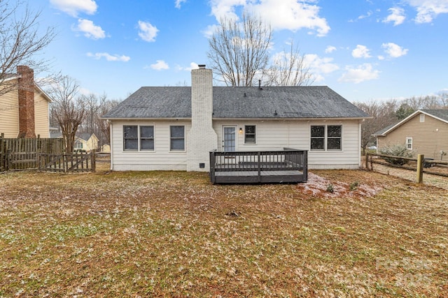 rear view of property with a chimney, a wooden deck, a lawn, and a fenced backyard