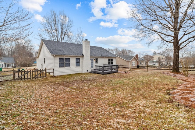 rear view of house featuring a lawn, a chimney, roof with shingles, fence, and a wooden deck