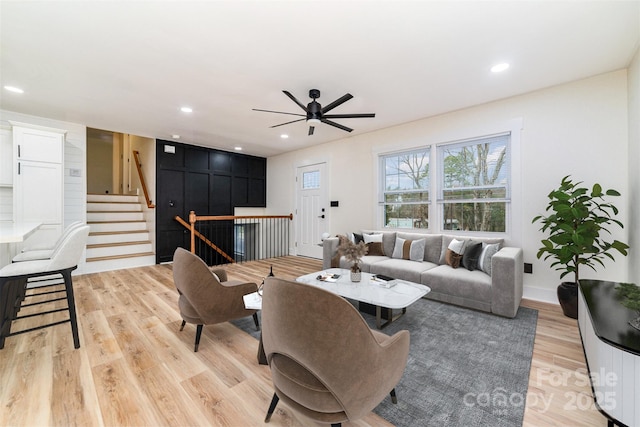 living area with light wood-style floors, stairs, baseboards, and recessed lighting