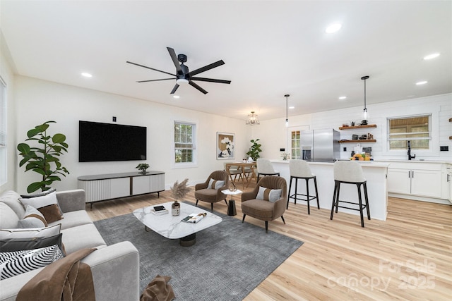 living area with recessed lighting, a ceiling fan, and light wood-style floors