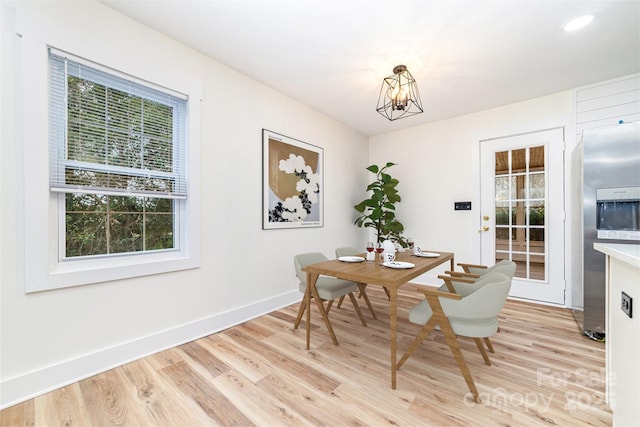 dining space featuring light wood-type flooring, baseboards, and a notable chandelier