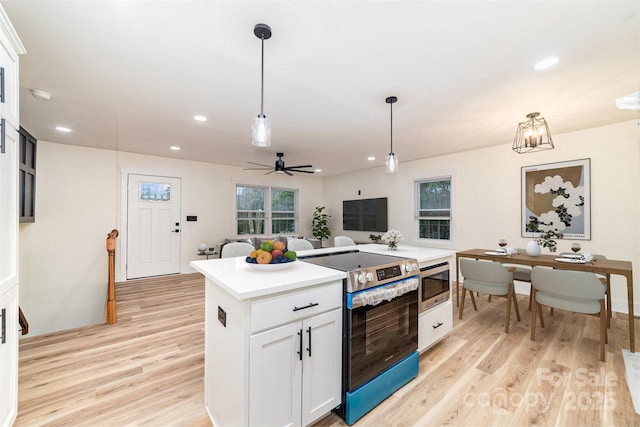 kitchen featuring stainless steel appliances, white cabinetry, light wood-style floors, light countertops, and pendant lighting