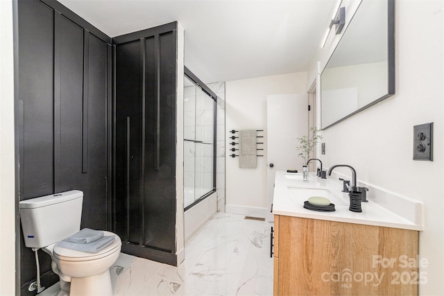 bathroom with enclosed tub / shower combo, toilet, vanity, baseboards, and marble finish floor