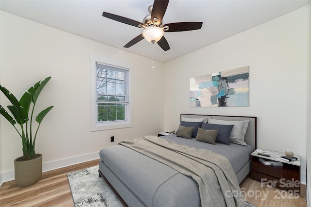 bedroom featuring light wood-type flooring, baseboards, and a ceiling fan