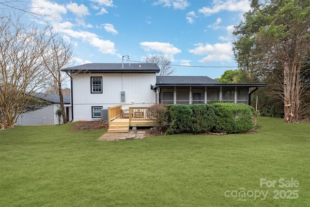 rear view of house featuring a sunroom, a deck, and a lawn