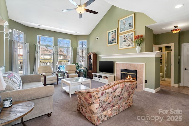 living area featuring ceiling fan, high vaulted ceiling, carpet flooring, baseboards, and a tiled fireplace