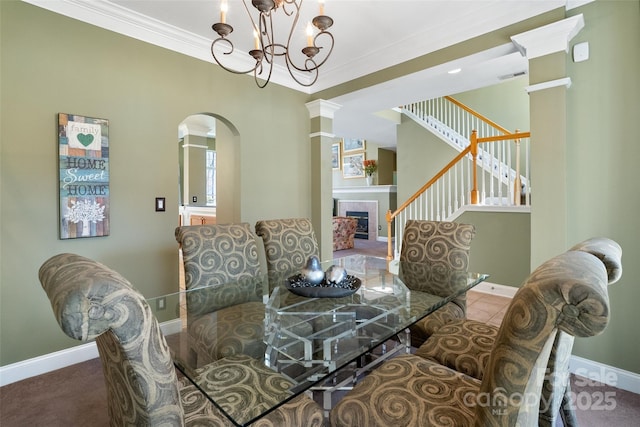 dining space with visible vents, ornamental molding, a tile fireplace, baseboards, and stairs