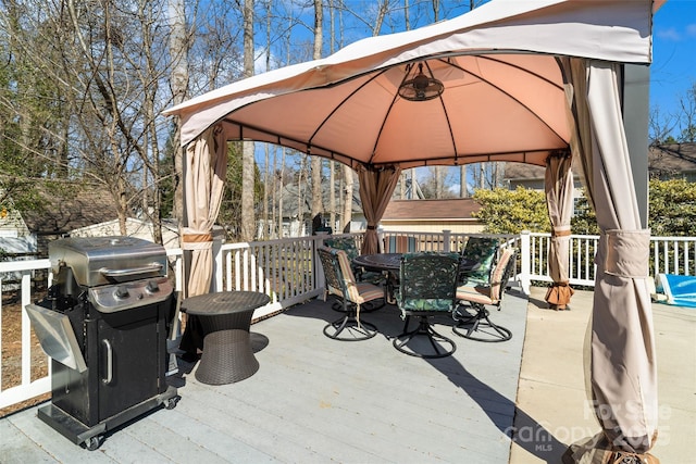 wooden terrace featuring outdoor dining area, area for grilling, and a gazebo