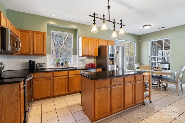 kitchen with stainless steel appliances, a sink, visible vents, a center island, and pendant lighting