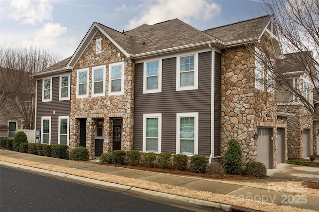 view of front of home with a garage, stone siding, a shingled roof, and concrete driveway