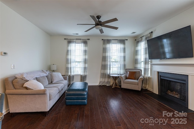 living area with a fireplace, dark wood finished floors, visible vents, and a ceiling fan