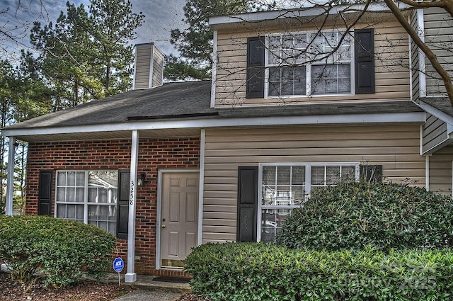 entrance to property featuring a chimney and brick siding