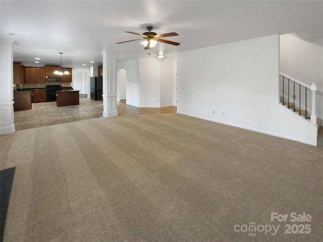 unfurnished living room with carpet floors, decorative columns, baseboards, and a ceiling fan