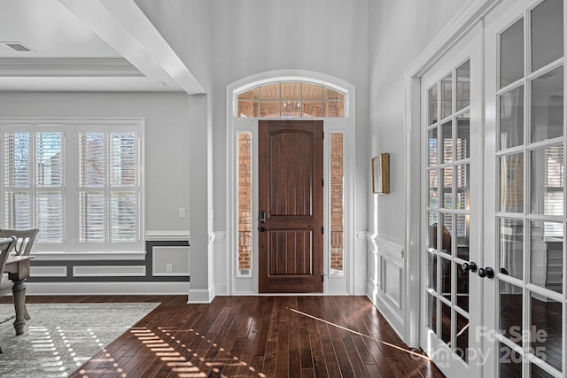 foyer with french doors, a wainscoted wall, visible vents, a decorative wall, and hardwood / wood-style flooring