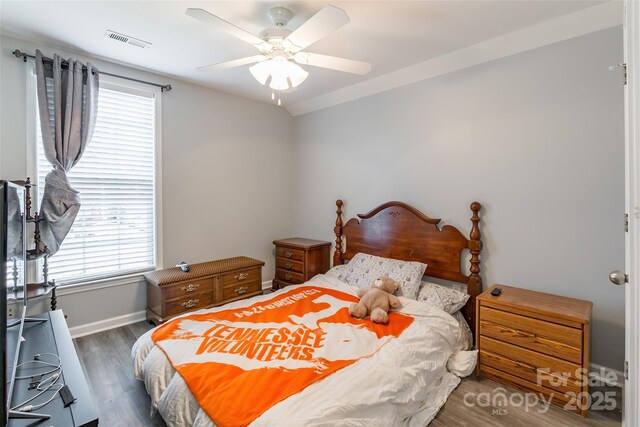 bedroom featuring baseboards, wood finished floors, visible vents, and a ceiling fan