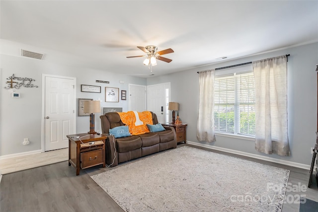 living area with wood finished floors, visible vents, and baseboards