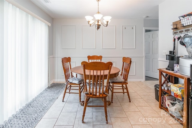 dining space featuring plenty of natural light, a notable chandelier, a decorative wall, and light tile patterned floors