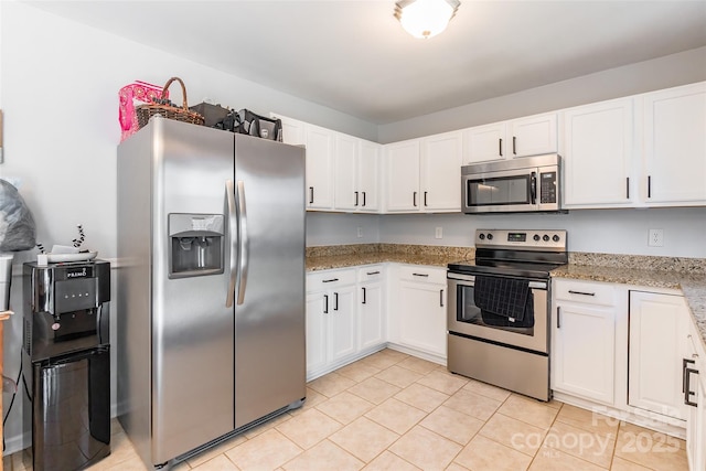 kitchen with light tile patterned floors, stainless steel appliances, light stone counters, and white cabinetry