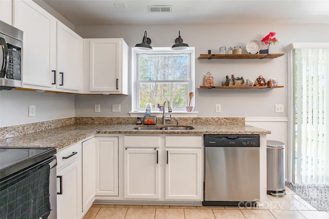 kitchen featuring stainless steel appliances, visible vents, white cabinetry, a sink, and light stone countertops