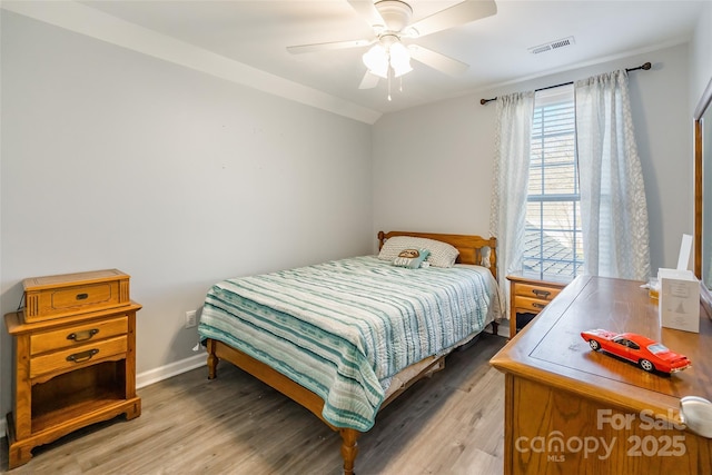 bedroom featuring light wood finished floors, baseboards, visible vents, and a ceiling fan