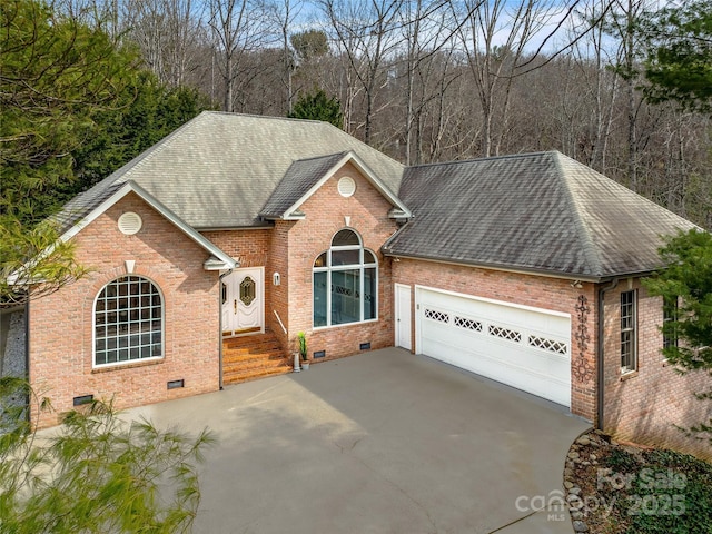 view of front of house with concrete driveway, roof with shingles, crawl space, an attached garage, and brick siding