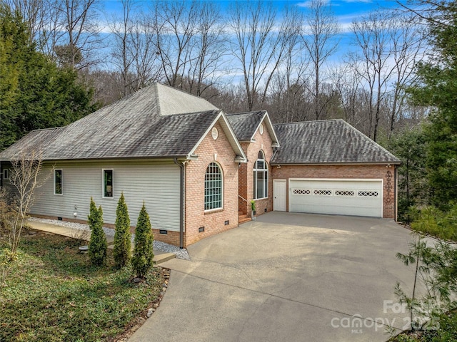 exterior space featuring brick siding, a shingled roof, crawl space, a garage, and driveway