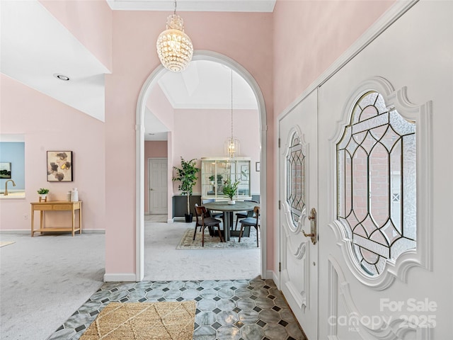 carpeted entryway featuring an inviting chandelier, baseboards, a high ceiling, and arched walkways