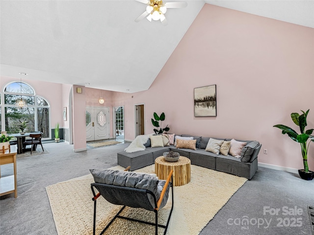 living room with ceiling fan, carpet floors, high vaulted ceiling, and baseboards