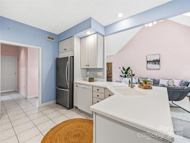 kitchen featuring light countertops, freestanding refrigerator, white cabinetry, white dishwasher, and a peninsula