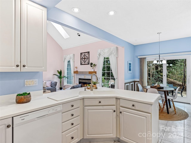 kitchen featuring a peninsula, a sink, light countertops, dishwasher, and lofted ceiling with skylight